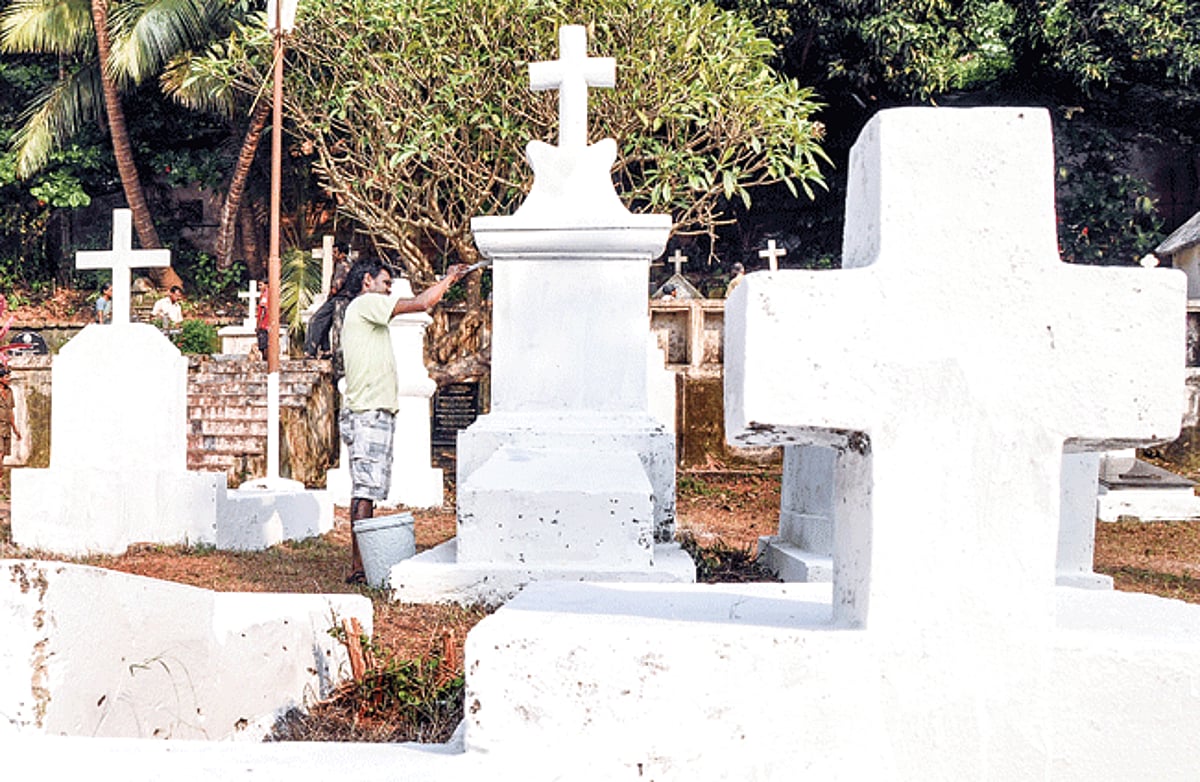 A CCP worker whitewashes graves at St Inez cemetery in preparation for All Souls Day on November 2.