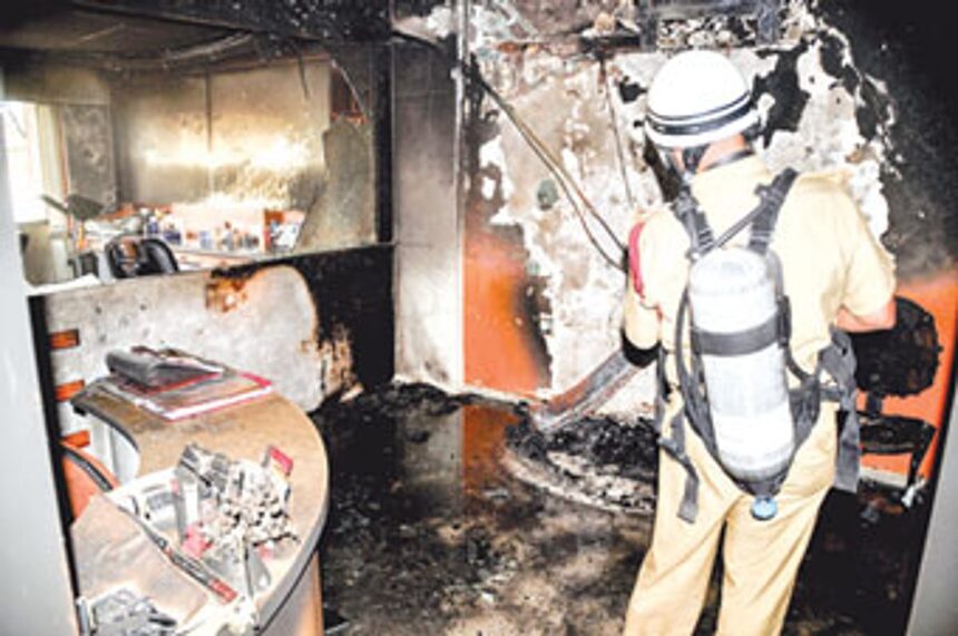 A firefighter of the Goa State Fire Force checks the remains after a fire gutted a clinic
