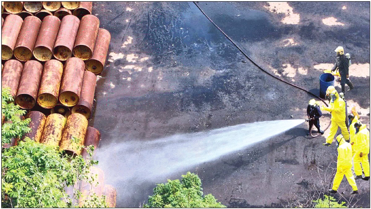 A firefighter sprays water on a pile of cylinders after chlorine gas leaked at a port area in Mumbai, on Wednesday