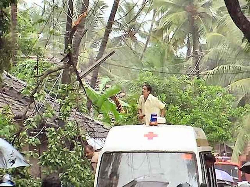 A man climbs on an ambulance in an effort to remove a branch entangled with the electricity cables.