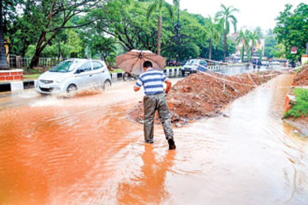 A man wades through ankle deep rain water accumulated due to incomplete construction of a drain