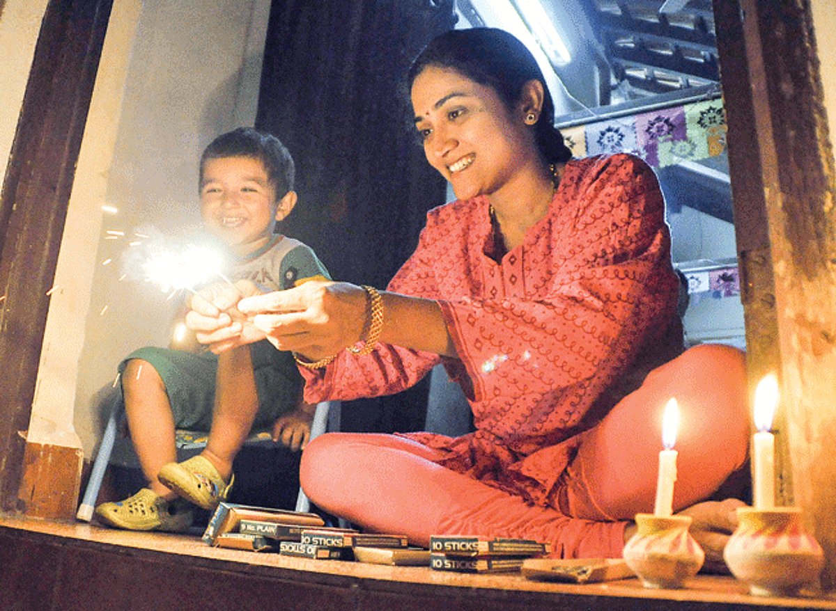 A mother amuses her child with sparkles on Diwali in Panjim.