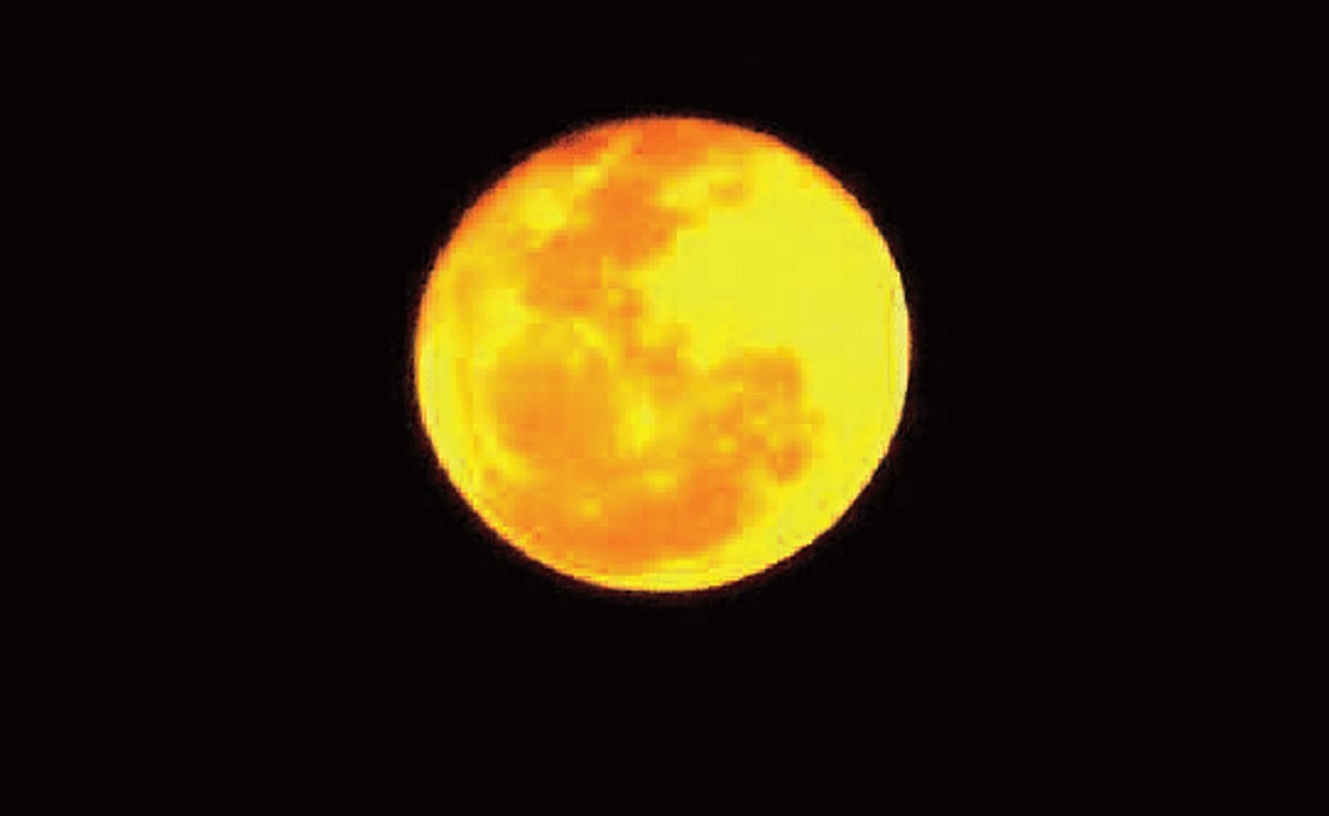 A view of the moon having an orange tone with dark orange spots which was noticed in the city.