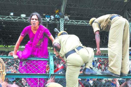 A woman crosses a fence as police officers attempt to control a crowd paying their final tributes to Chief Minister of Andhra Pradesh Y S Rajasekhara Reddy at the Lal Bahadur Shastri Stadium in Hyderabad on Friday.