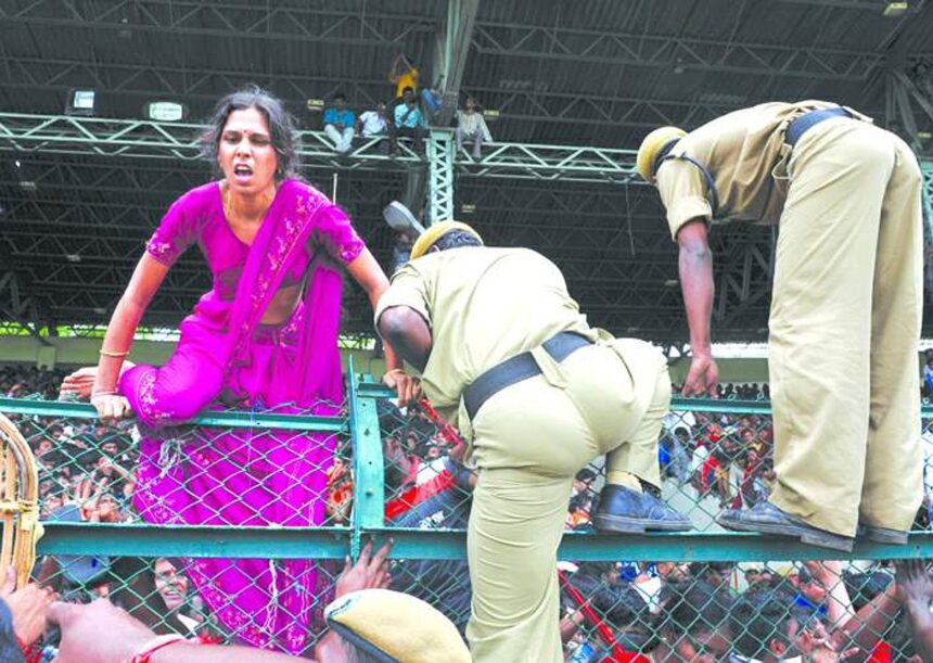 A woman crosses a fence as police officers attempt to control a crowd paying their final tributes to Chief Minister of Andhra Pradesh Y S Rajasekhara Reddy at the Lal Bahadur Shastri Stadium in Hyderabad on Friday.