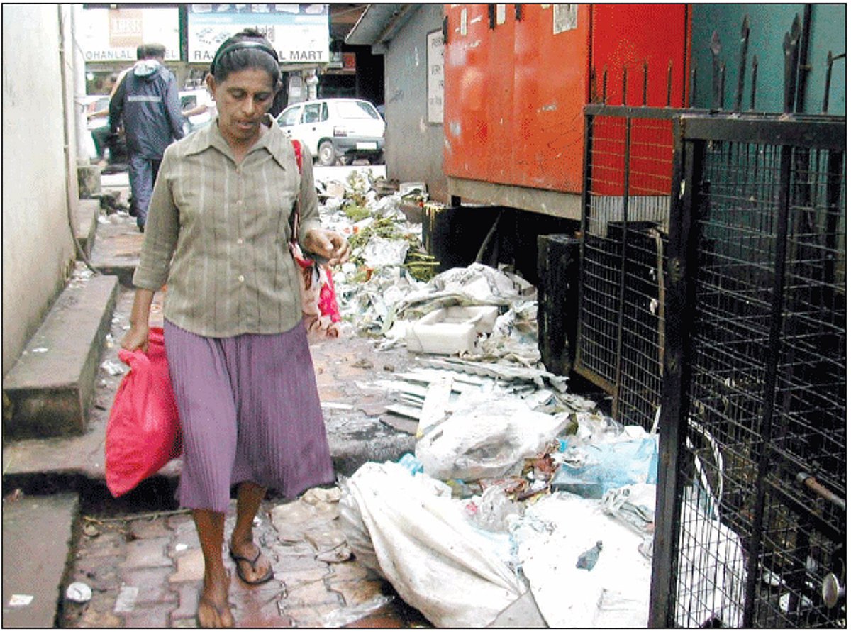 A woman walks past garbage at the busy Sadekar lane.