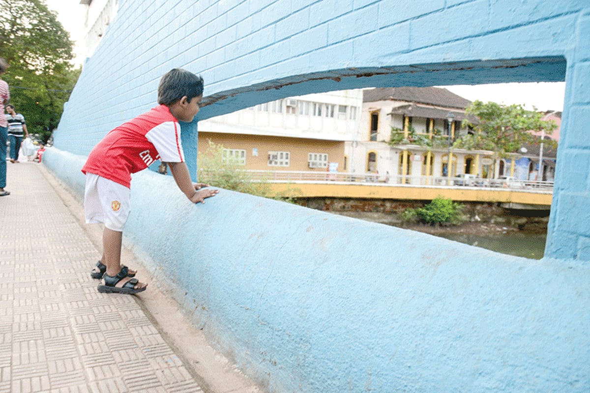 A young lad peeps through the gap of the foot bridge of which the iron grills have collapsed, making it dangerous for students in the vicinity