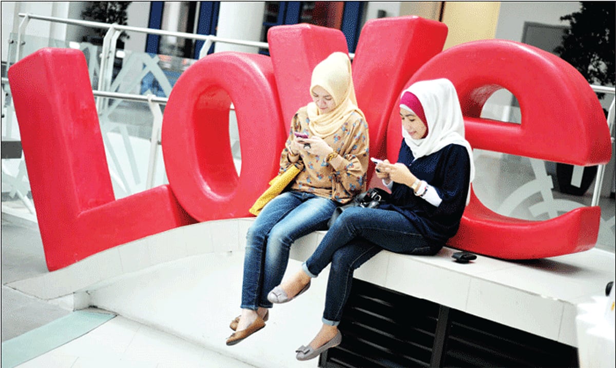 ALL FOR LOVE: Two women enjoy social networking by using their mobile phone devices in Jakarta on Sunday. In Indonesia,40 million Facebook users and 20 million Tweeters comprise the world's third-largest Facebook community and fifth-biggest on Twitter.