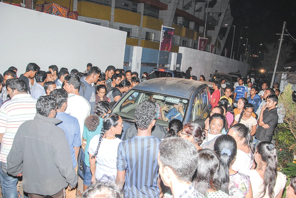 Agitated Fatorda residents demand to know the status of the passes for the games from an official seated inside the car.