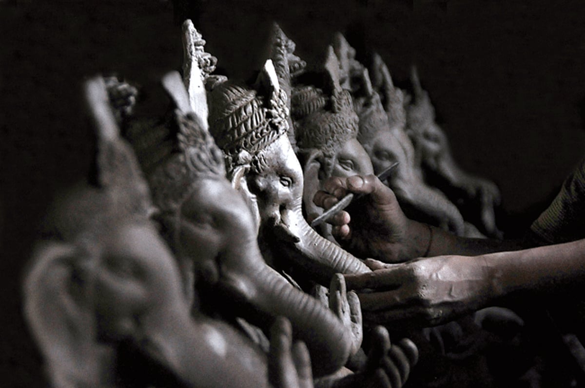 BRUSH WITH CLAY: A traditional artiste makes clay idols of Lord Ganesha in his  workshop at Pormbupa, on Tuesday