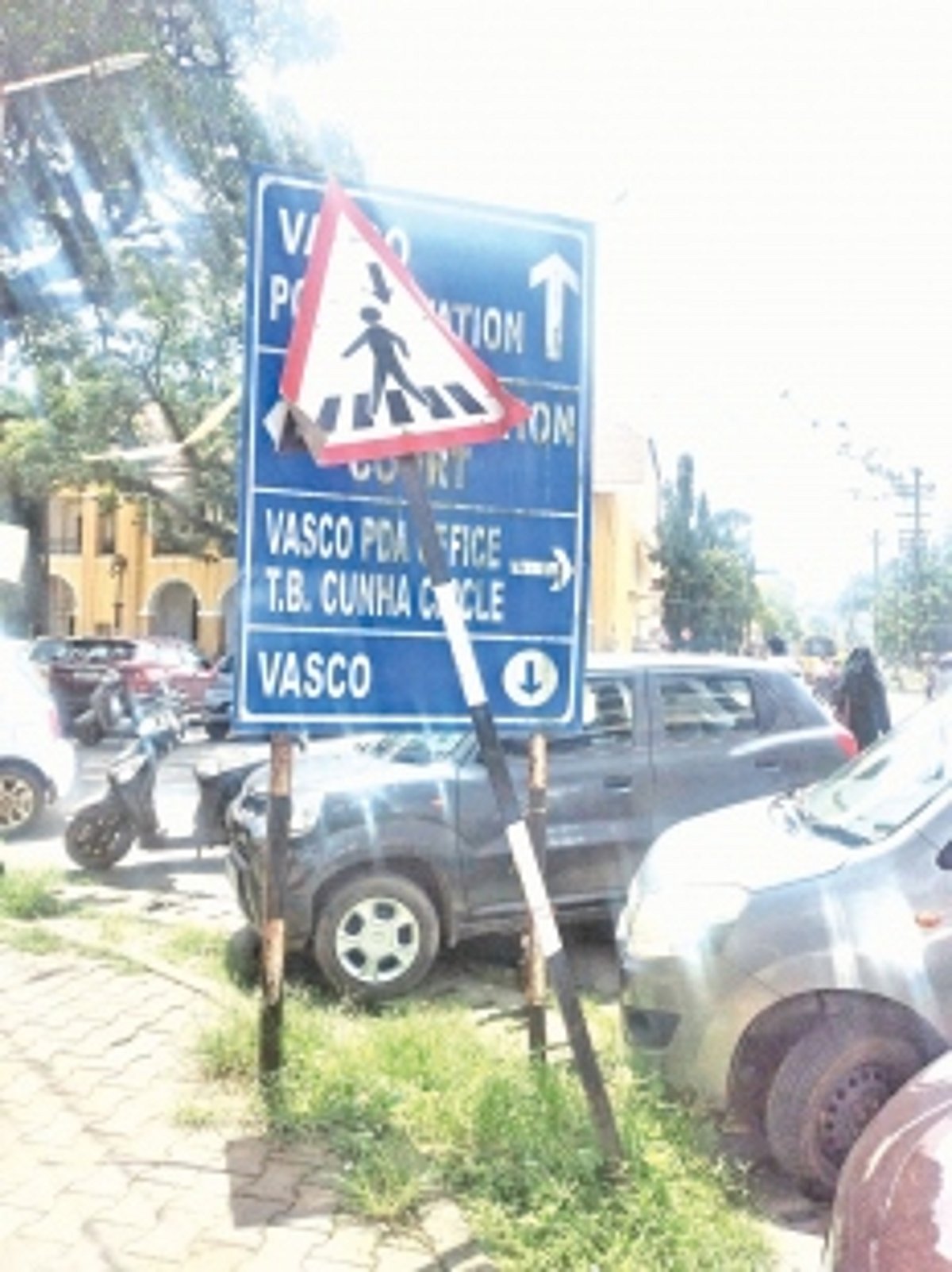 Bent road-sign covers another sign showing direction