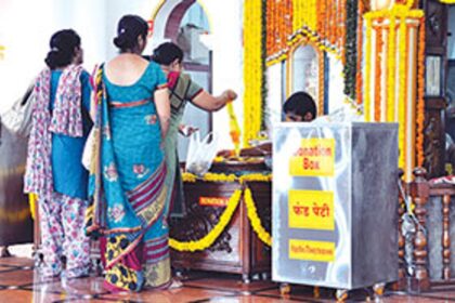 Devotees make floral offerings next to a donation box