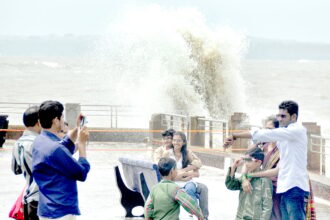Domestic tourists capture their memorable moments in camera as huge waves battering the jetty in the background, at Dona Paula.