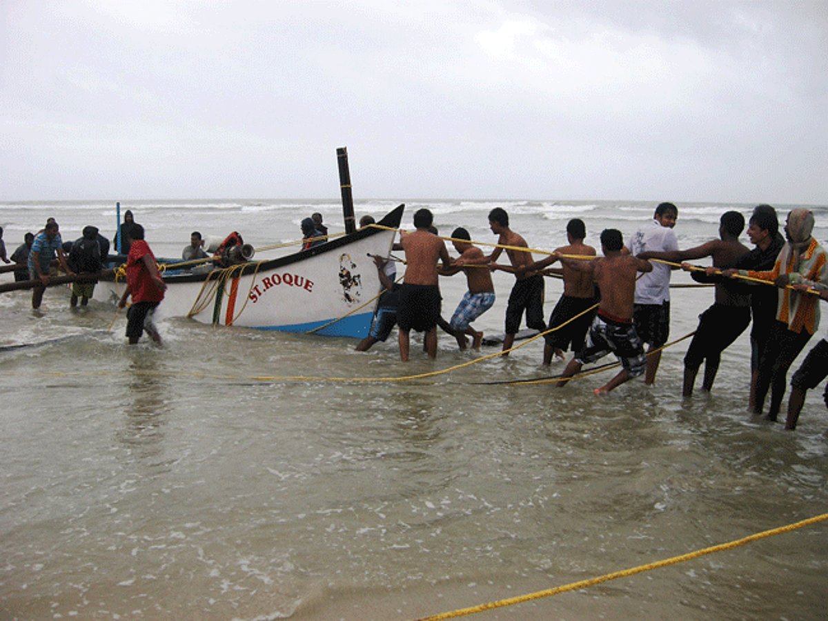 Fishermen tow one of the ill-fated motorised canoes which capsized on Sunday.