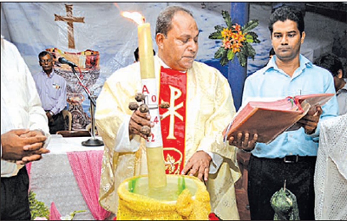 Fr Oscar Quadros dips the Paschal Candle in holy water during the Easter vigil services at Clergy Home, Porvorim to mark the resurrection of Jesus Christ.