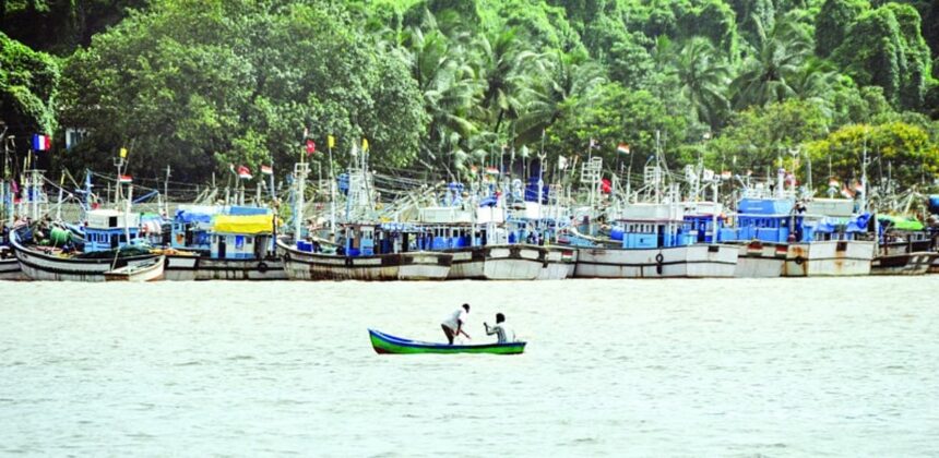 Local fishermen cast their net from a canoe opposite the anchored trawlers in the Mandovi river.