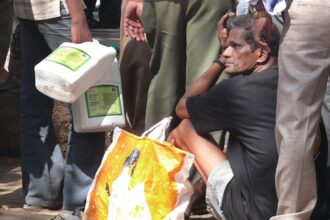 MERA NUMBER KAB AAYEGA? A man takes some rest as he squats in a queue for fuel at a petrol pump in the Capital City on Friday.