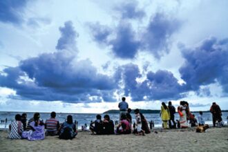 People enjoy the evening while dark pre-monsoon clouds hover