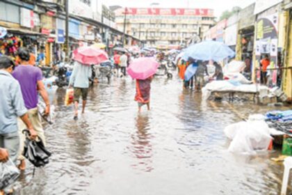 People wade through the flooded Mapusa market.