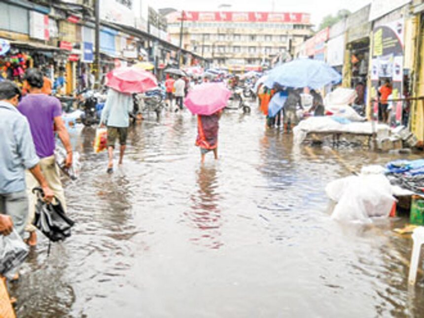 People wade through the flooded Mapusa market.