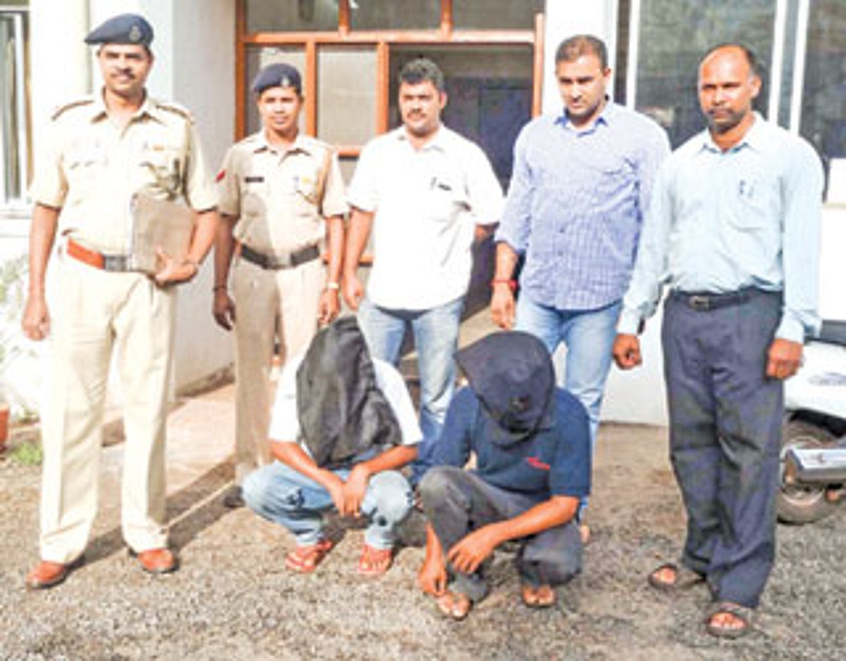 Police along with the two accused (squatting) who have been arrested on charges of molesting a schoolgirl.