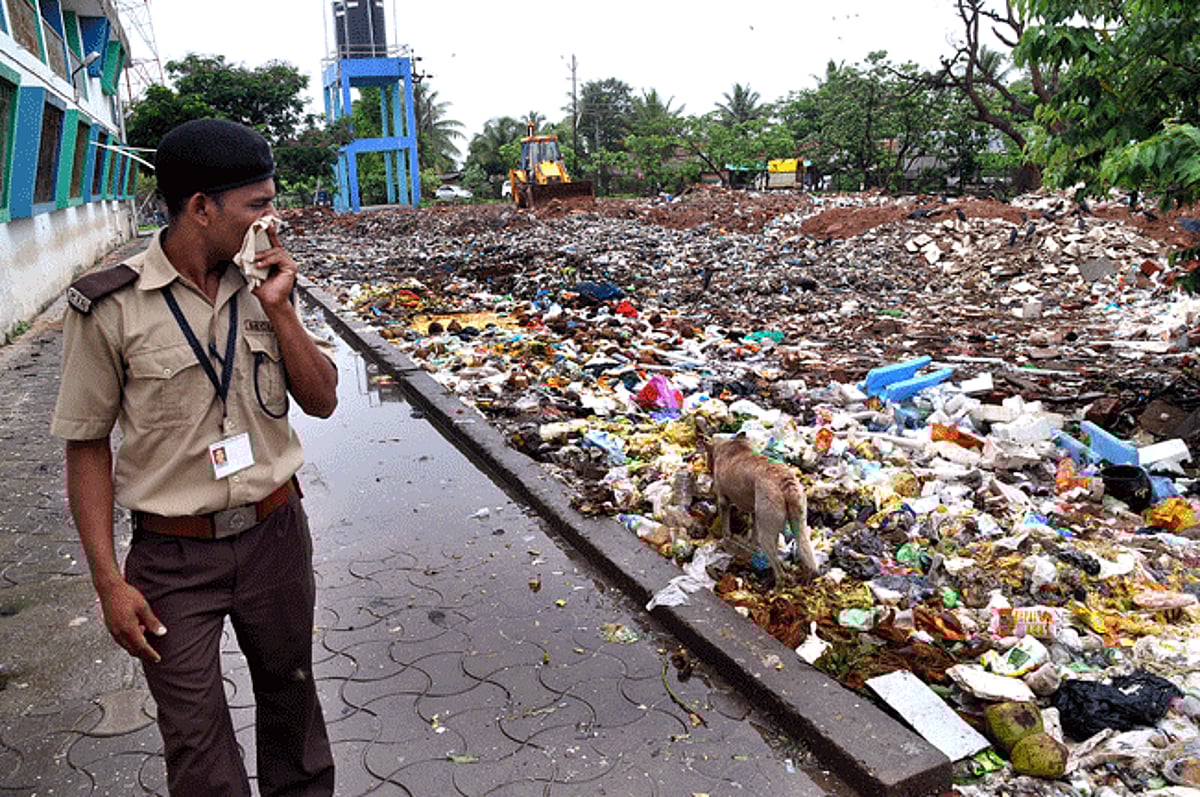 STENCH?MOST?FOUL: Unable to bear the stench,  a security guard covers his nose while walking  next to the garbage comprising food leftovers and medical waste emptied next to Yatri Niwas at the GMC complex at Bambolim.Saturday.