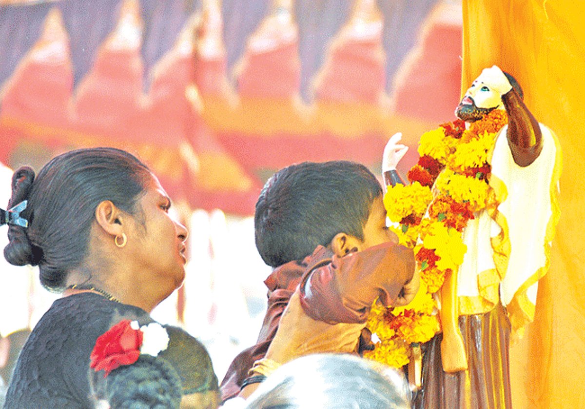 TOUCH OF FAITH: A woman lifts her child to kiss the statue of St Francis Xavier at the Basilica of Bom Jesus, Old Goa on Tuesday, on the feast of the saint.