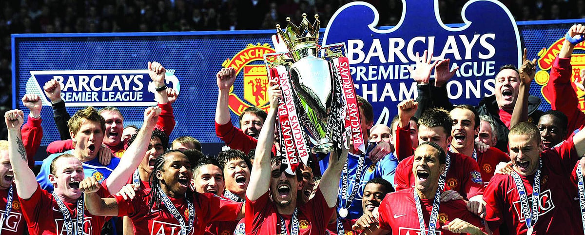 The Manchester United team celebrates with the English Premier League trophy after drawing 0-0 with Arsenal in the English Premier League football match at Old Trafford, Manchester, north-west England.