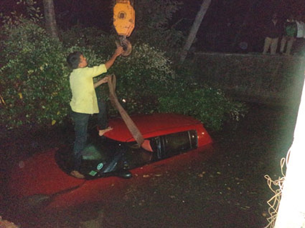 The car being removed from the culvert with the help of a crane.