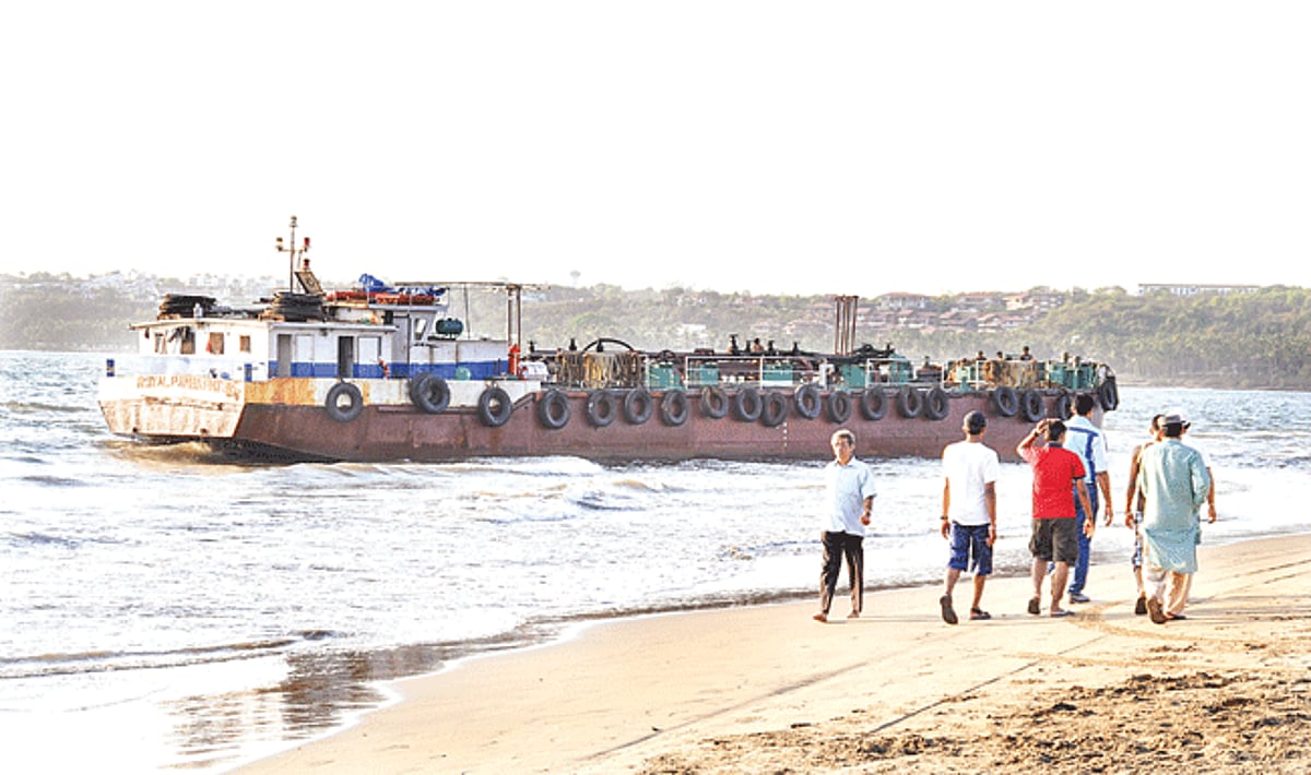 Tourist walk past a grounded (diesel tanker) barge Royal Pamba PNJ 315 at Miramar beach on Tuesday.