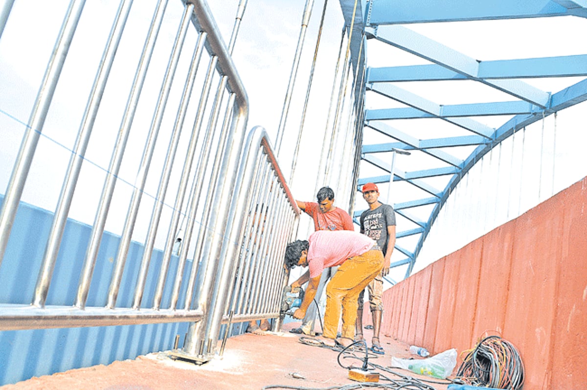 Workers fix stainless steel railings along both sides of the main span on the Aldona-Calvim bridge.
