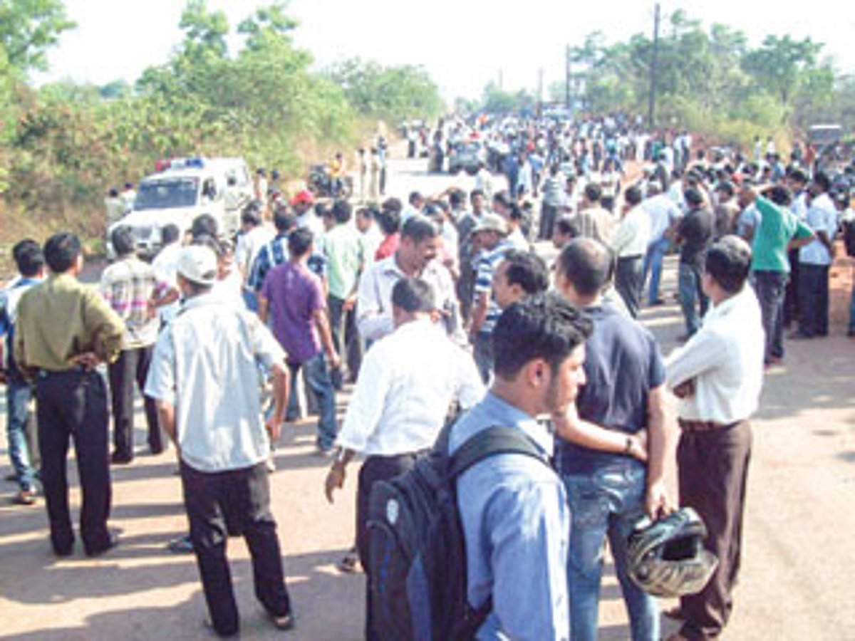 Workers gather at the entry point of Kundaim Industrial Estate on Thursday.
