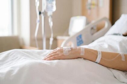 patients arm with an intravenous iv drip resting on pristine white hospital bedding photo